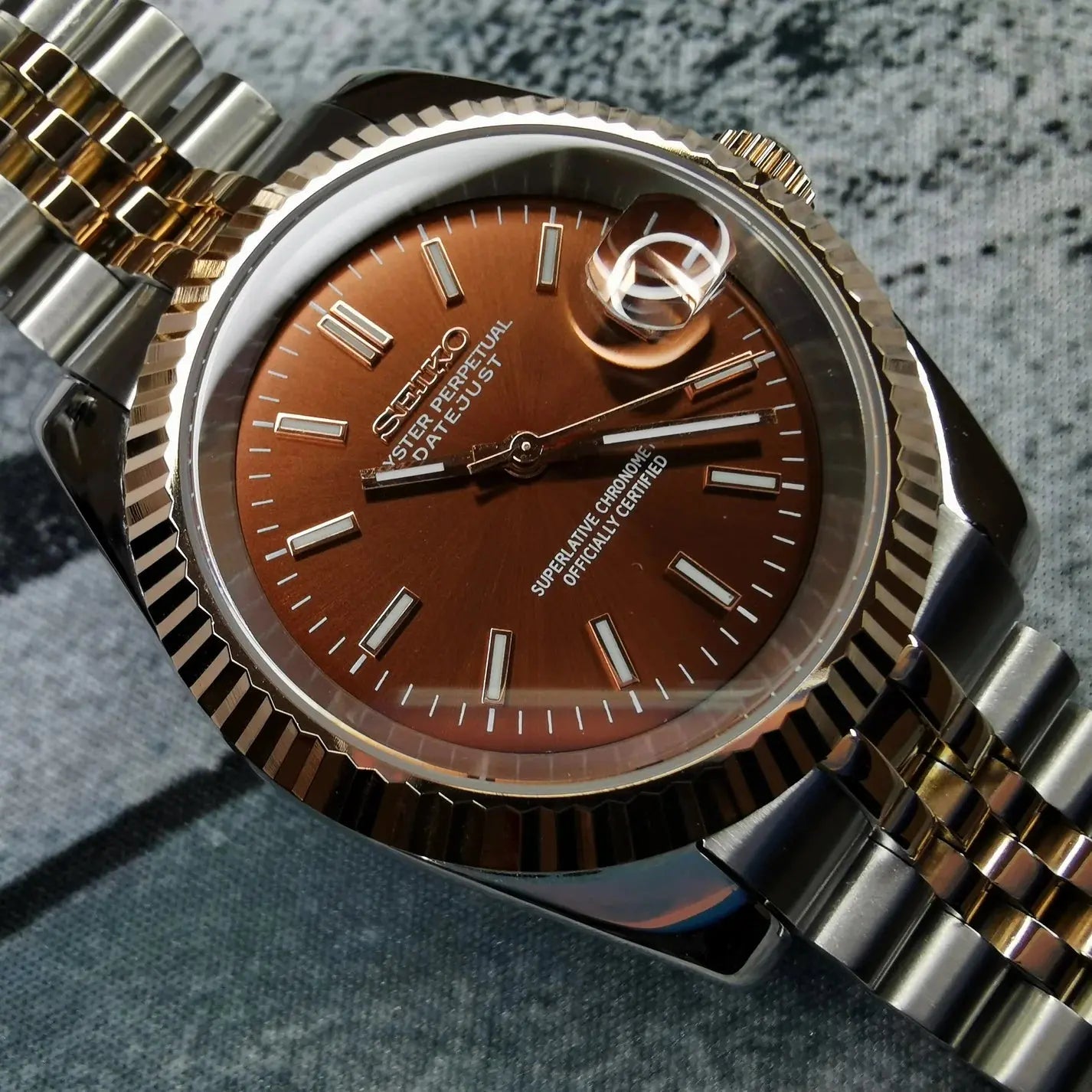 Montre seiko modifiee modele datejust avec un cadran couleur tabac, boitier en acier inoxydable poli et bracelet assorti, alliant elegance et personnalisation unique.