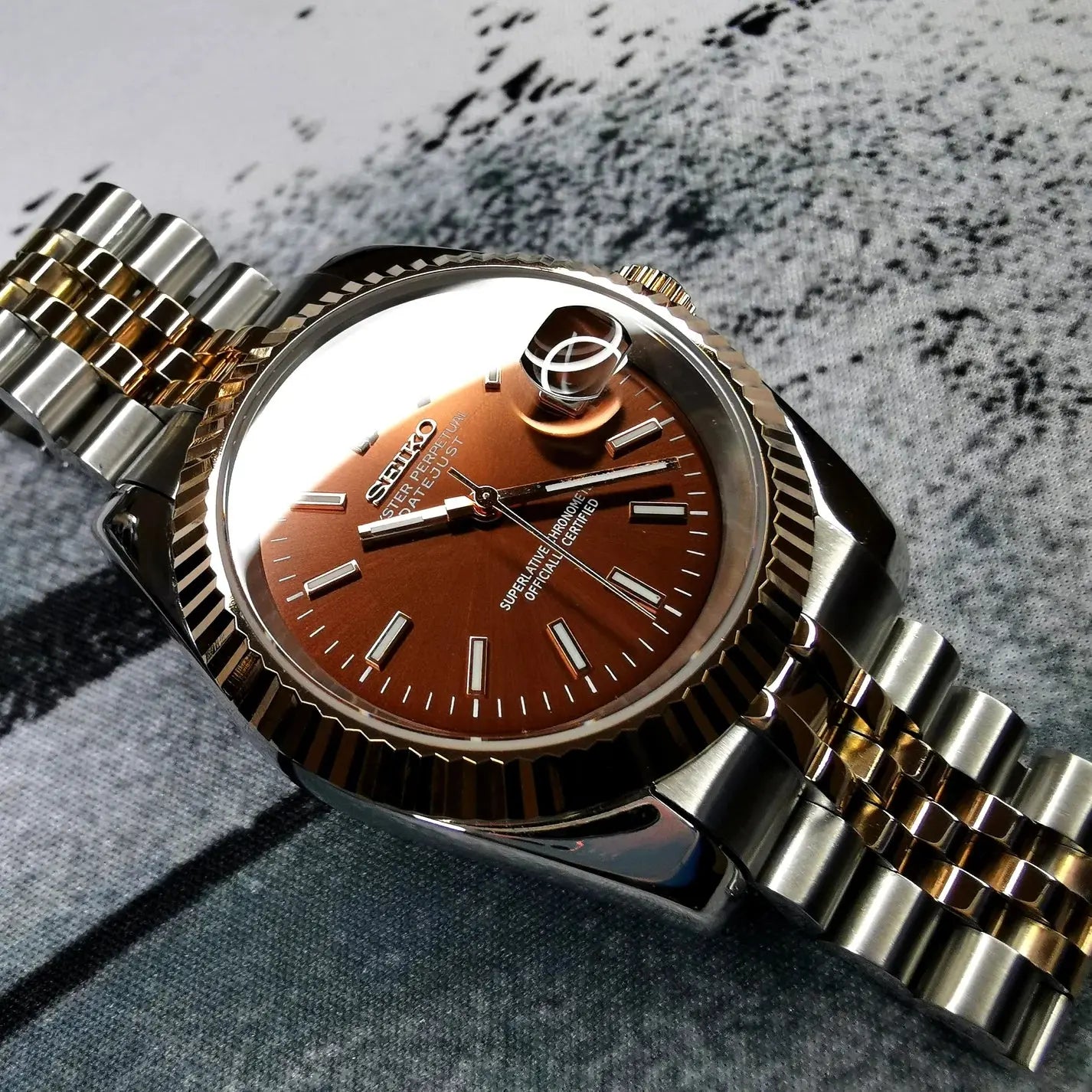Montre seiko modifiee modele datejust avec un cadran couleur tabac, boitier en acier inoxydable poli et bracelet assorti, alliant elegance et personnalisation unique.